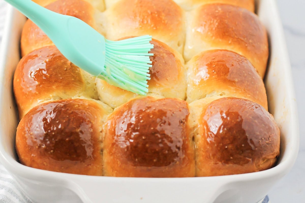 Brushing baked rolls with butter.