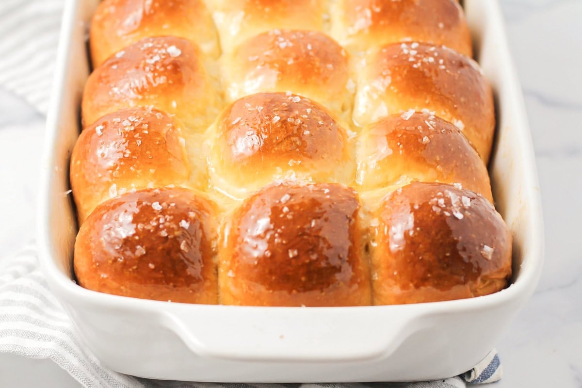 A baking pan of Parker House Rolls topped with honey butter.