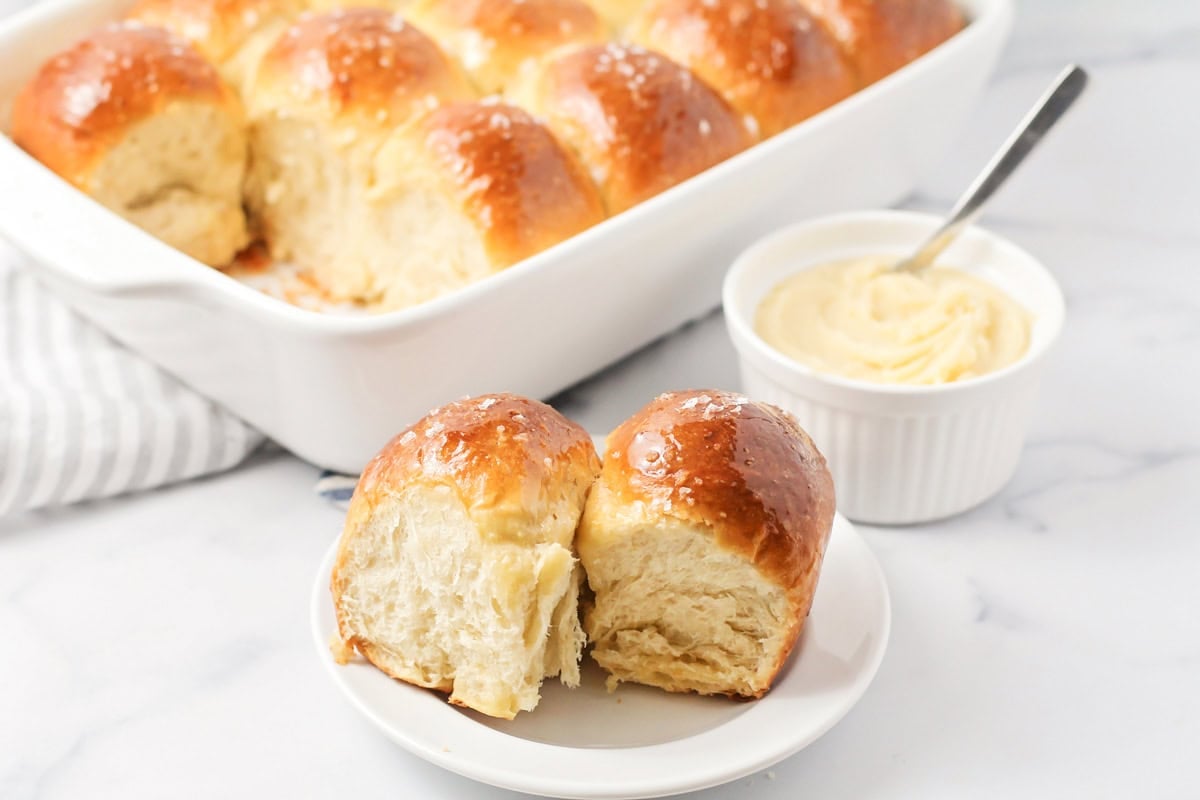 Two buttered Parker House Rolls on a white plate.