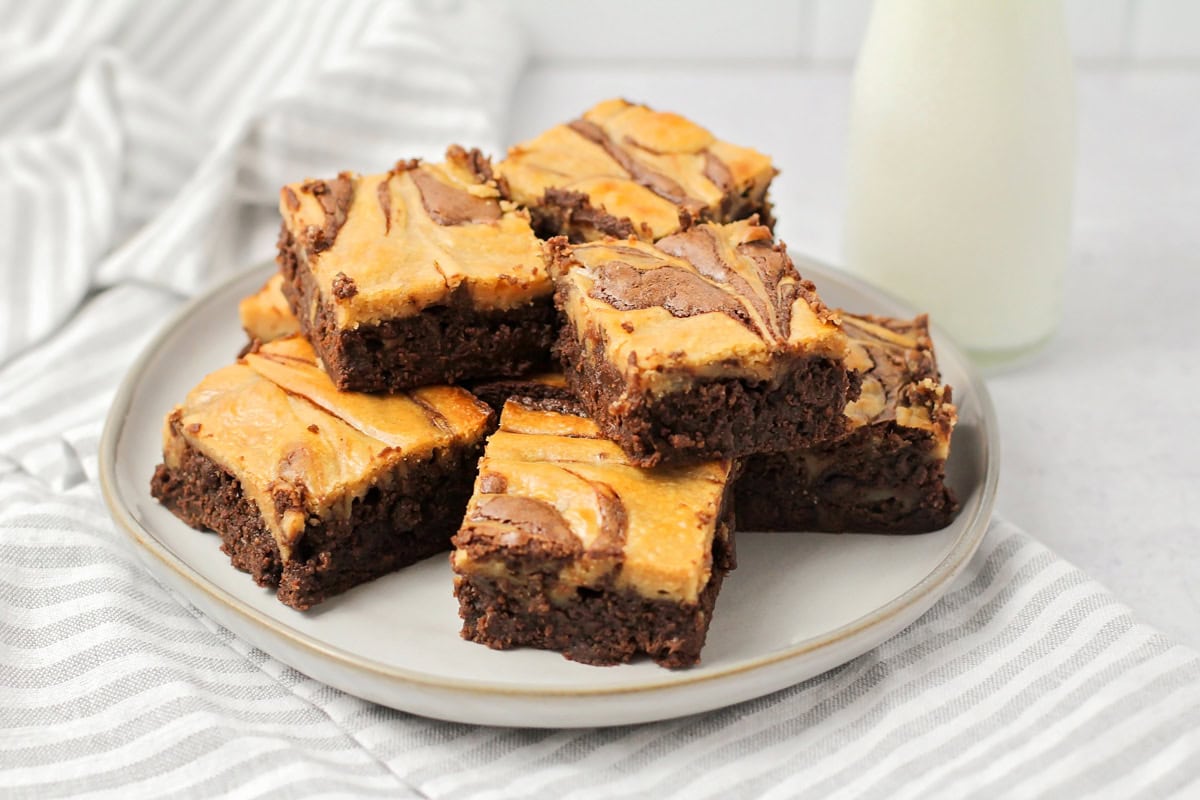 Peanut butter brownies stacked on a white plate.