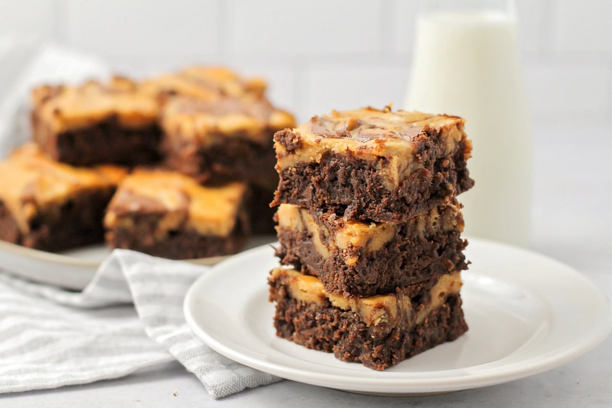 Peanut butter brownies stacked on a white plate.