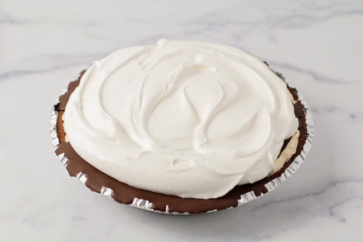 Whipped cream on top of a peanut butter pie.