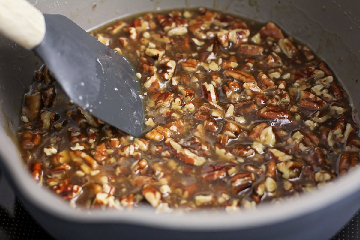 Pecans in a sweet sauce in a pan on the stove.