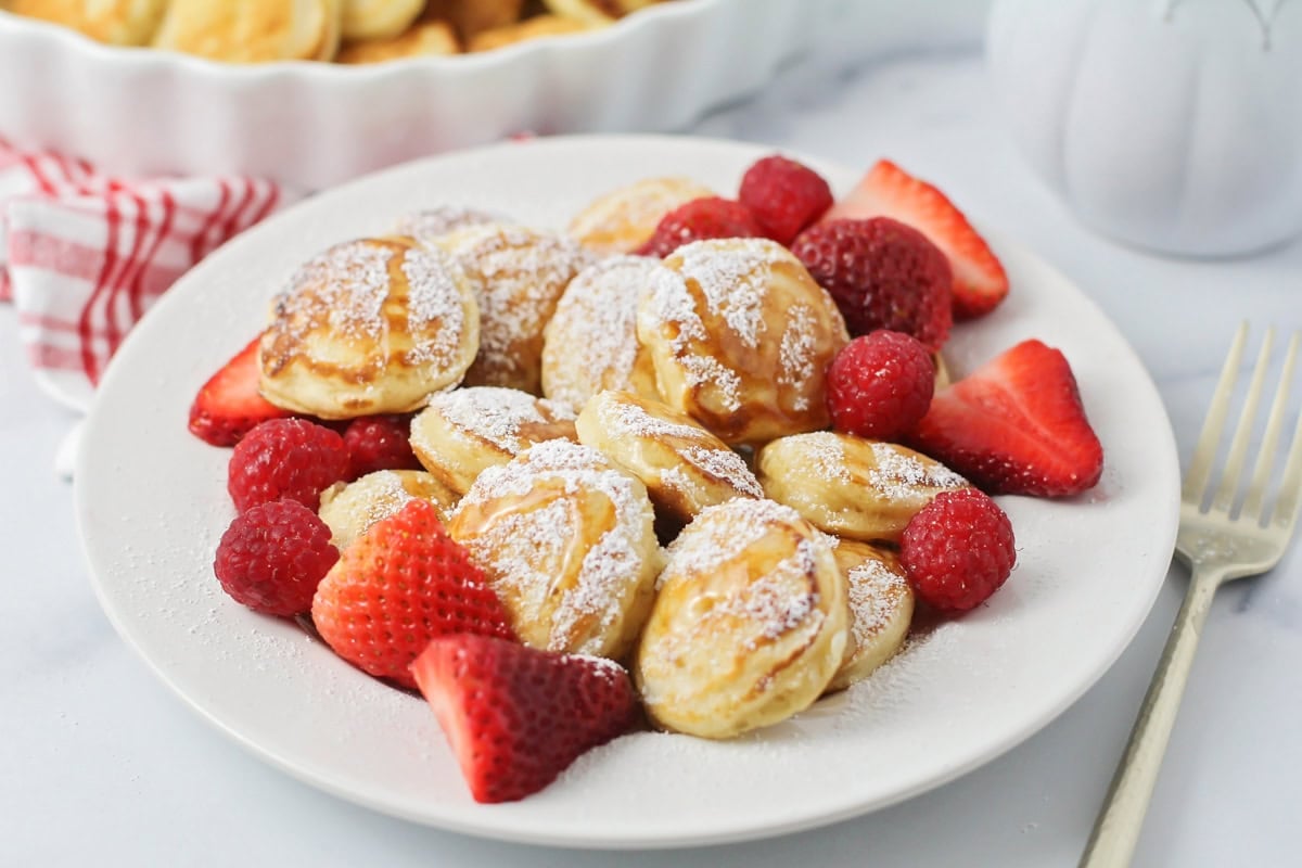 Poffertjes topped with powdered sugar and fresh berries.