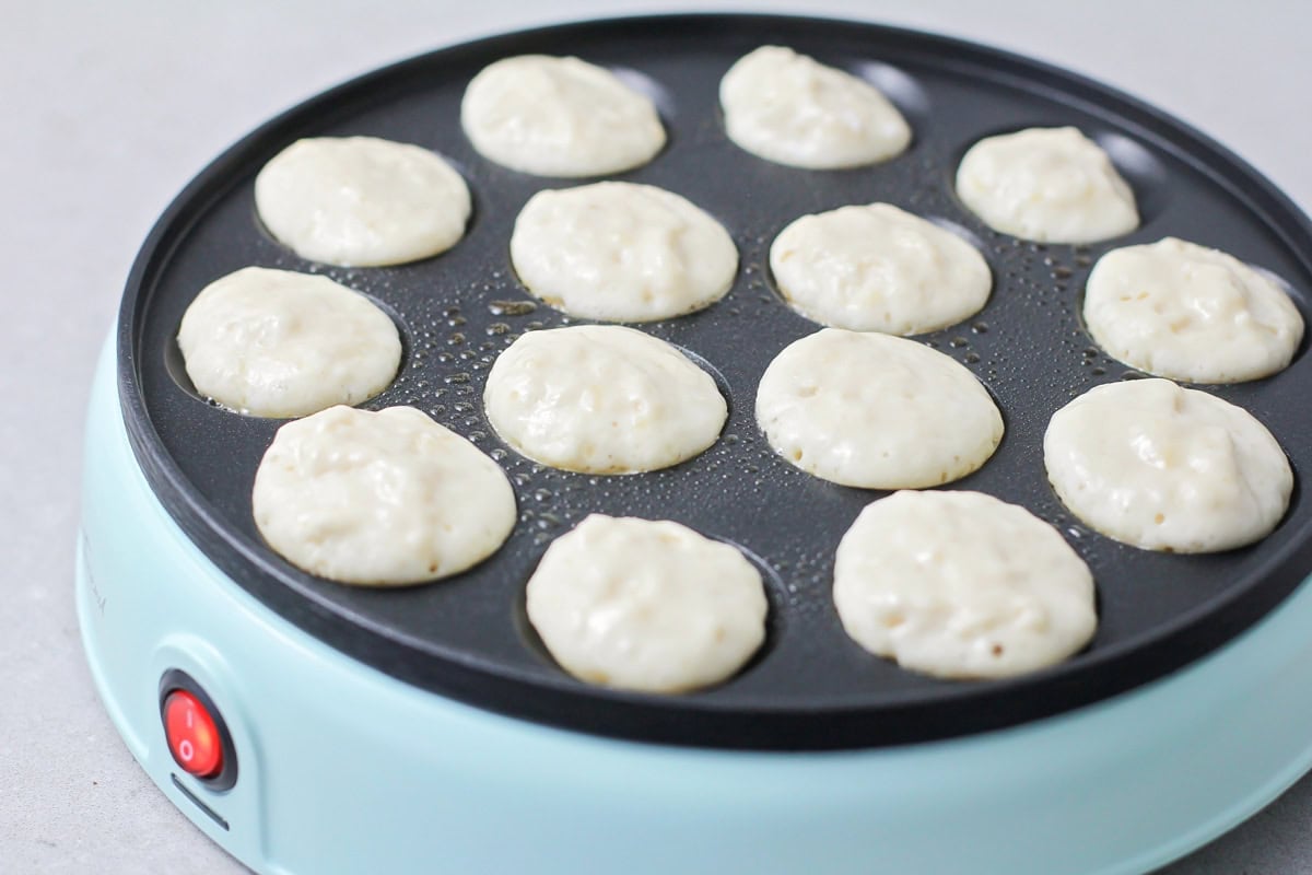 Adding pancake batter to a poffertjes pan.