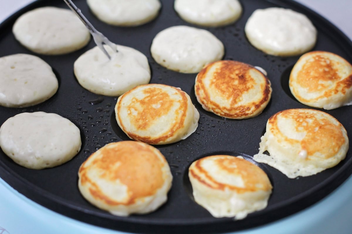 Flipping the mini pancakes with a skewer.