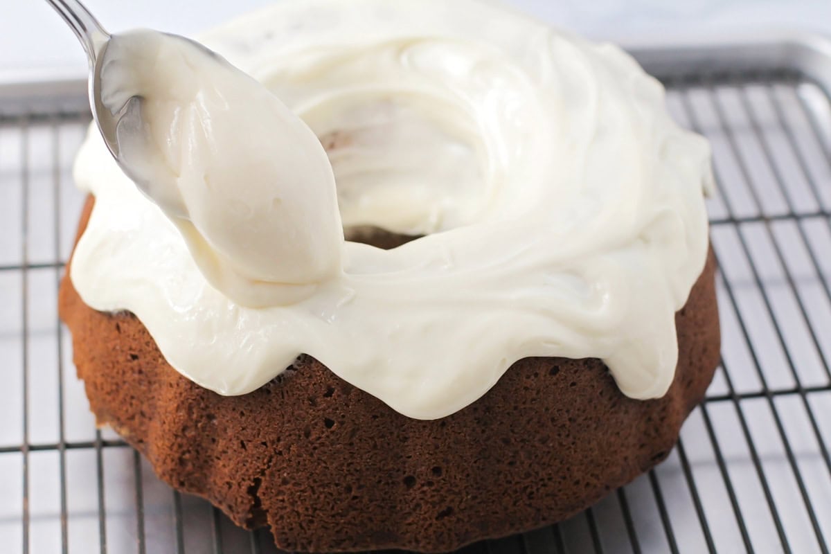 A frosted bundt cake on a cooling rack.