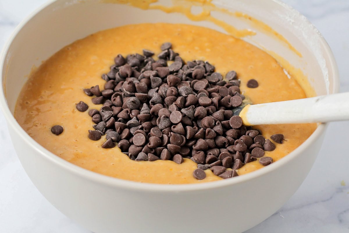 Adding chocolate chips to pumpkin batter.