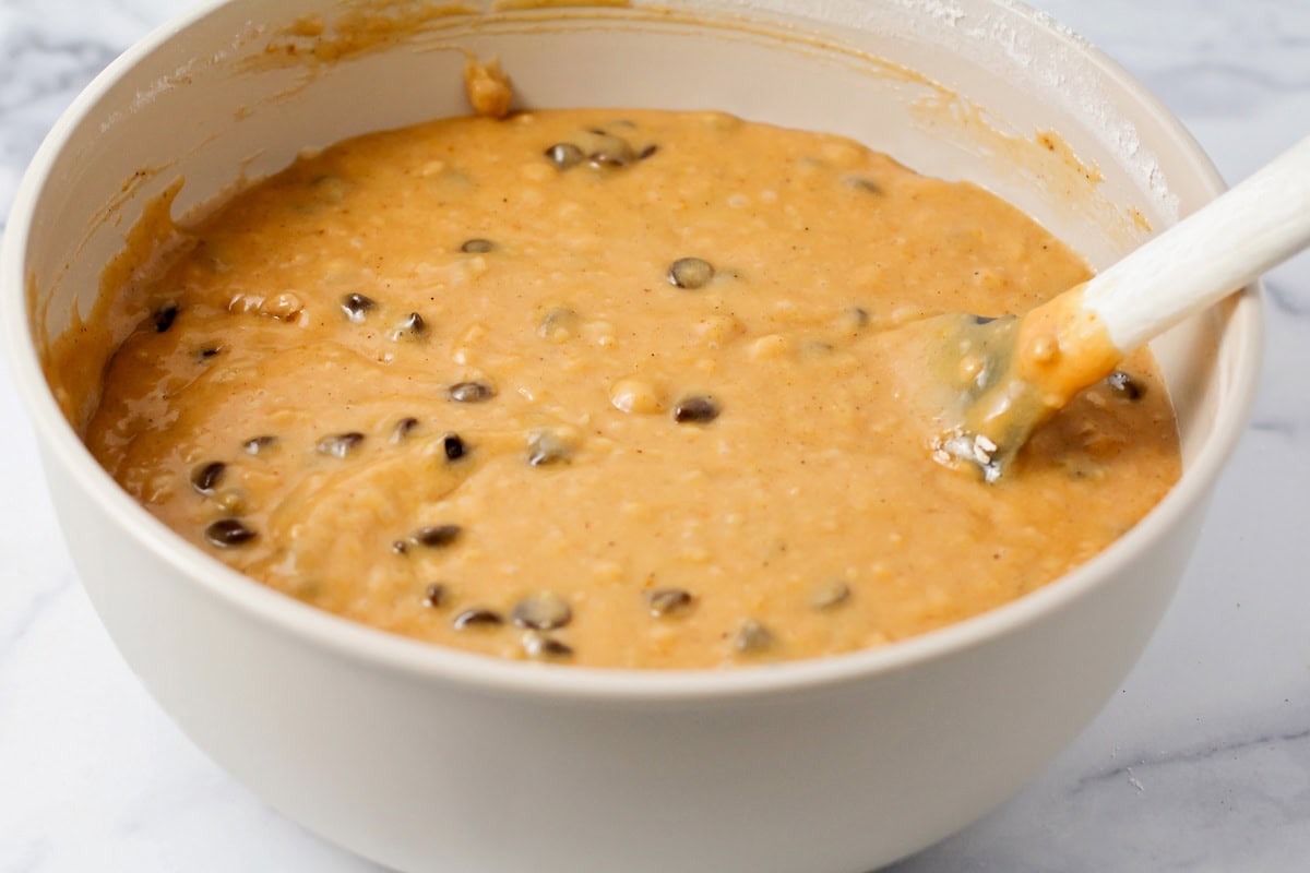 Mixing chocolate chips into pumpkin batter.