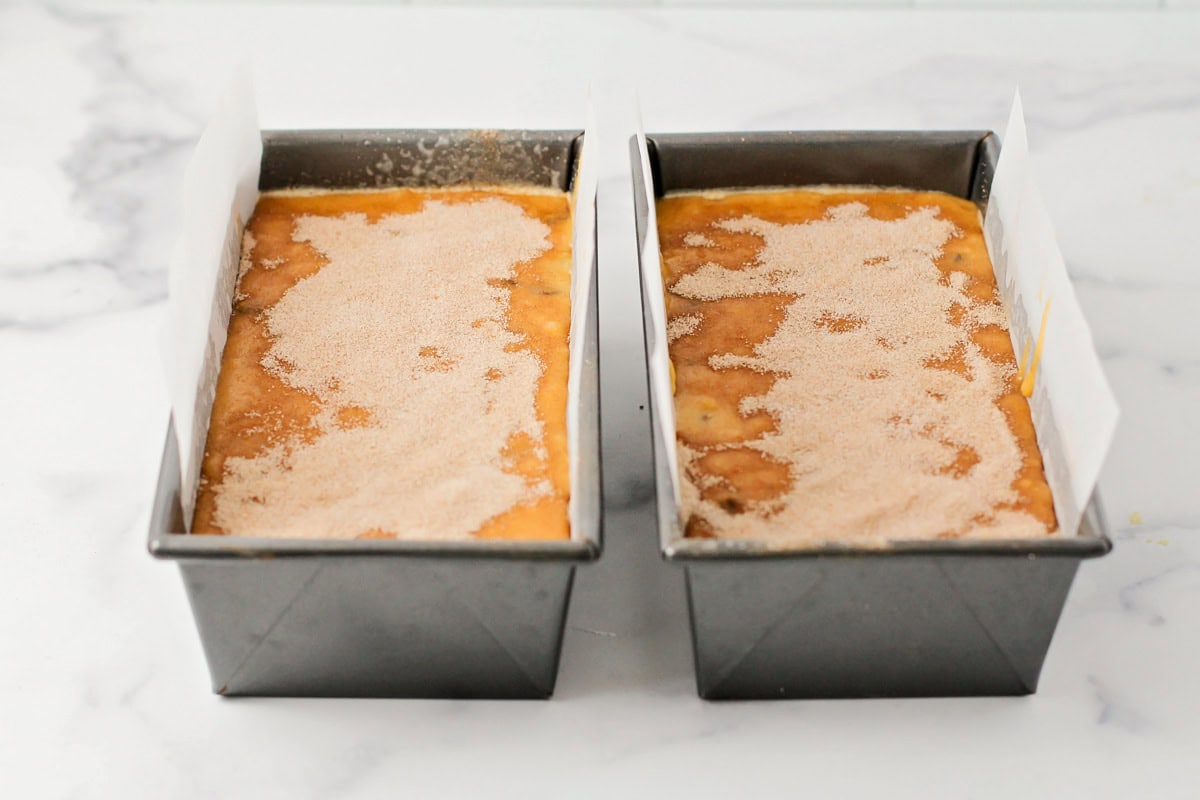 Two loaf pans filled with pumpkin chocolate chip bread batter.