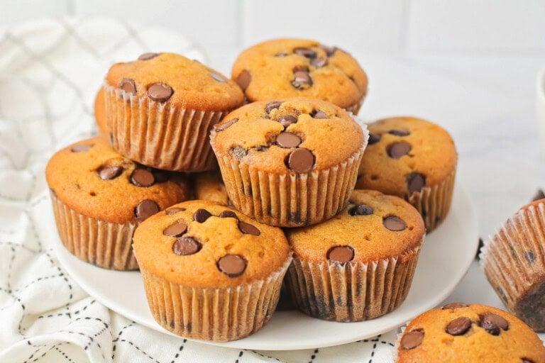 Several pumpkin chocolate chip muffins stacked on a white platter.