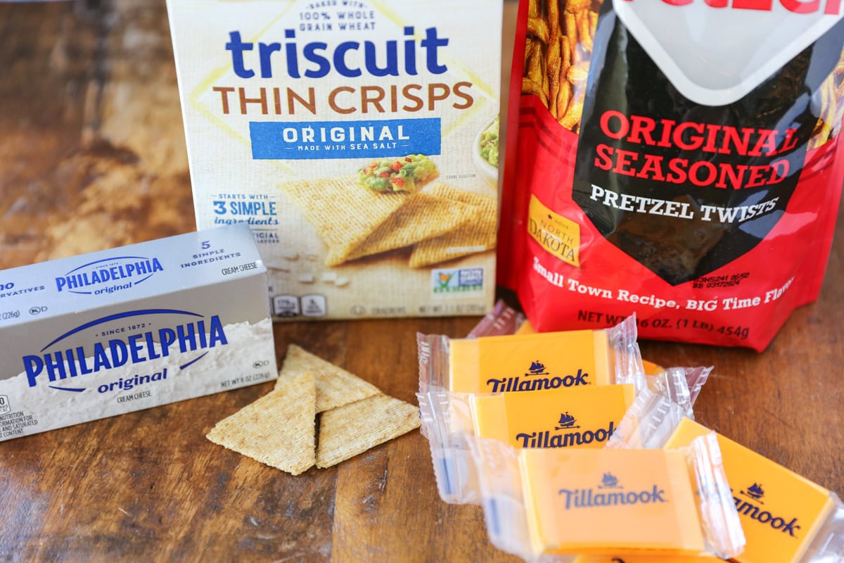 Ingredients for cheese and crackers on a kitchen table.