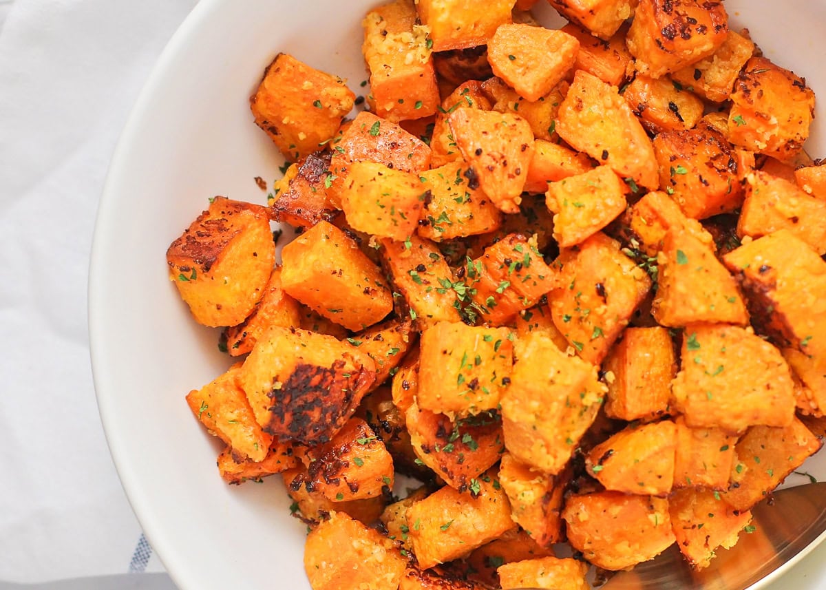 Roasted sweet potato cubes in white bowl.