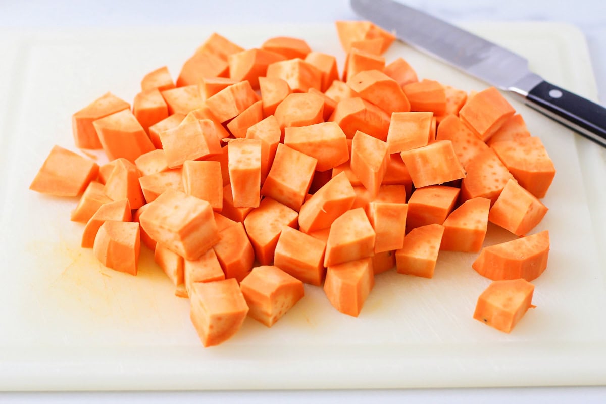 Sweet potatoes, peeled and cubed on cutting board.