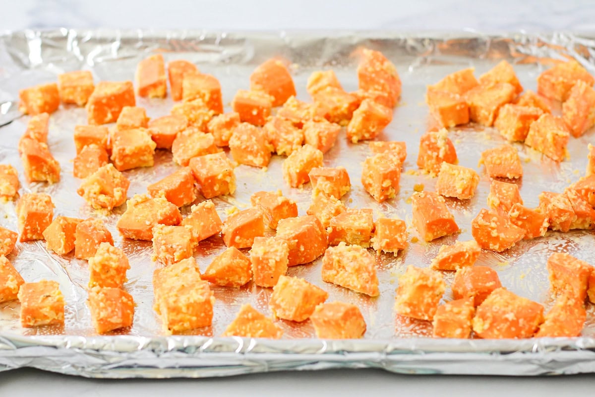 Roasted sweet potato cubes on foil lined baking sheet.