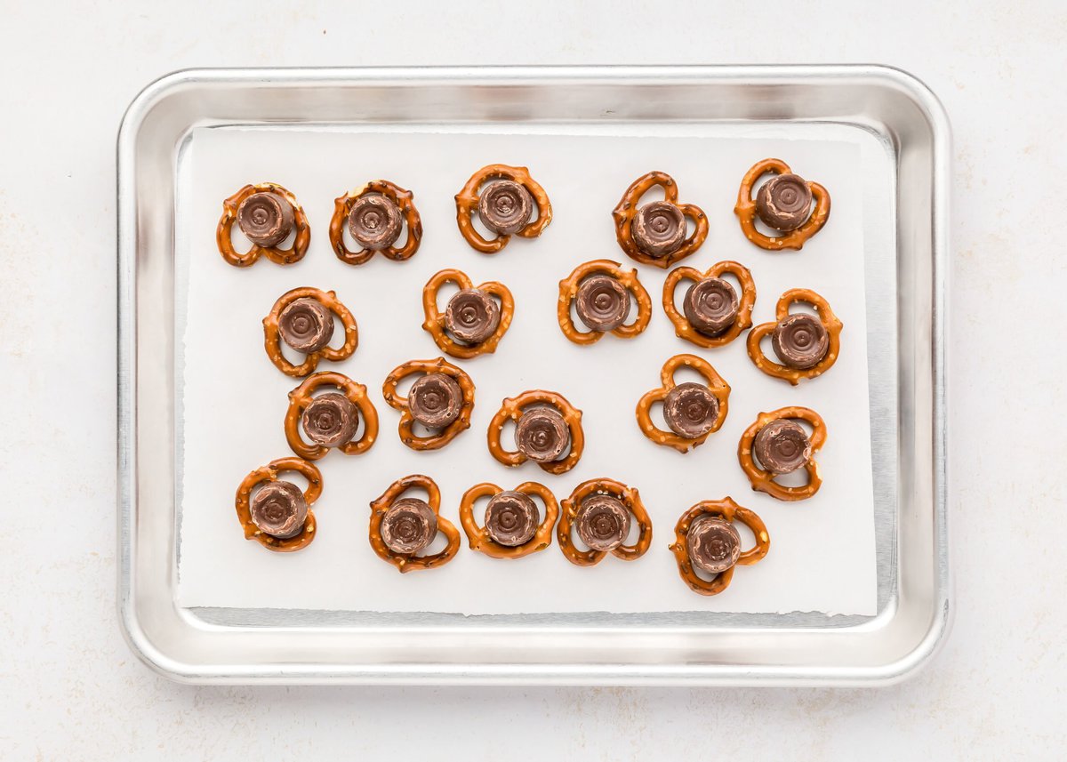 Pretzels topped with rolos on a lined baking sheet.