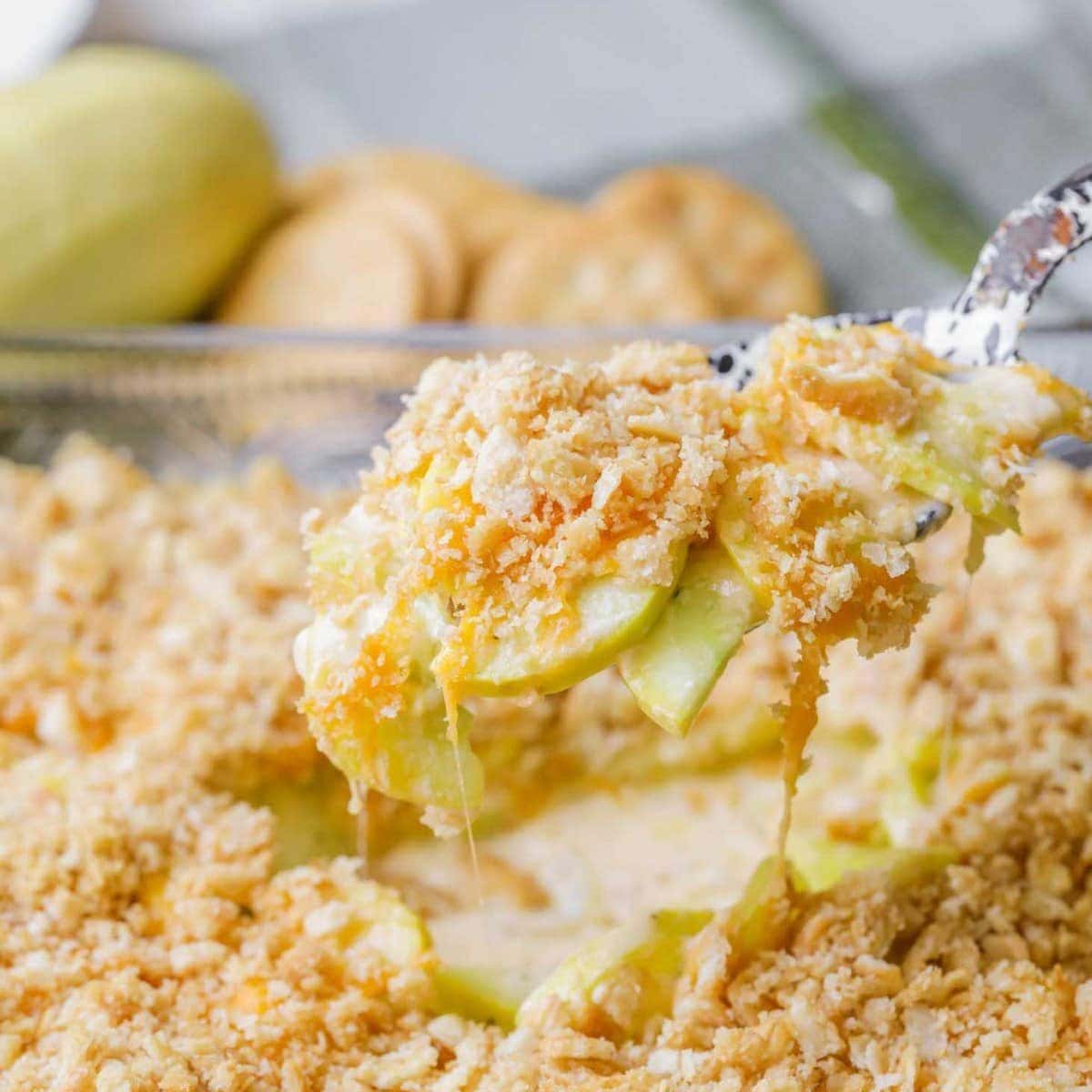 Squash casserole being dished out of baking pan.