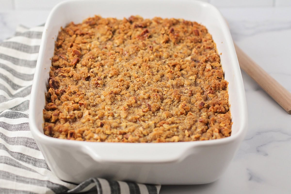 A white baking dish of sweet potato souffle on a kitchen counter.