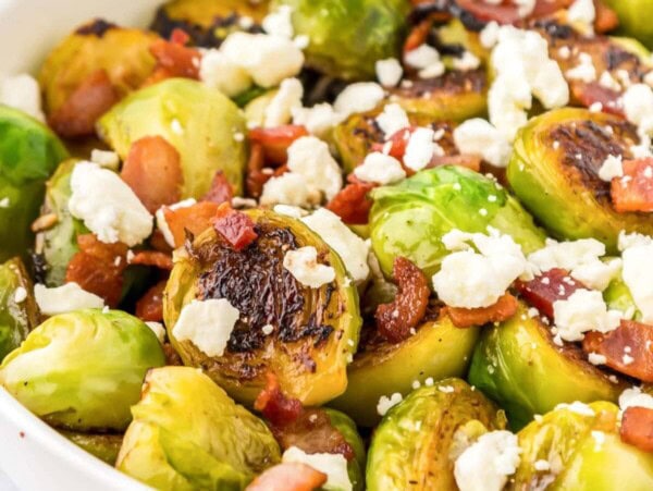 Thanksgiving Brussels Sprouts in bowl with bacon and cheese sprinkled on top.
