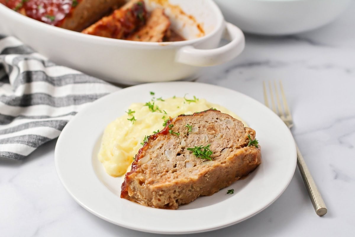 A slice of turkey meatloaf served with mashed potatoes.