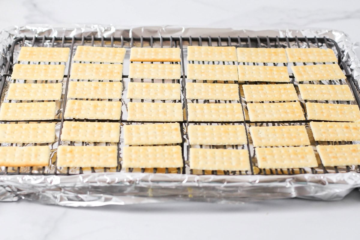 Crackers on a wire rack atop a lined baking sheet.