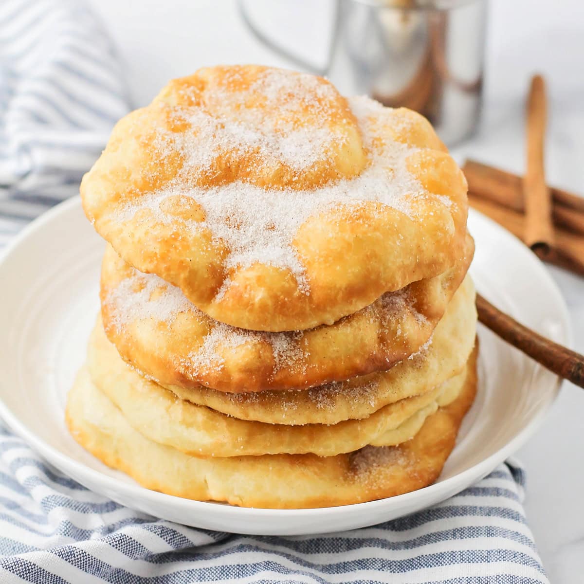 Bunuelos stacked on a white plate.