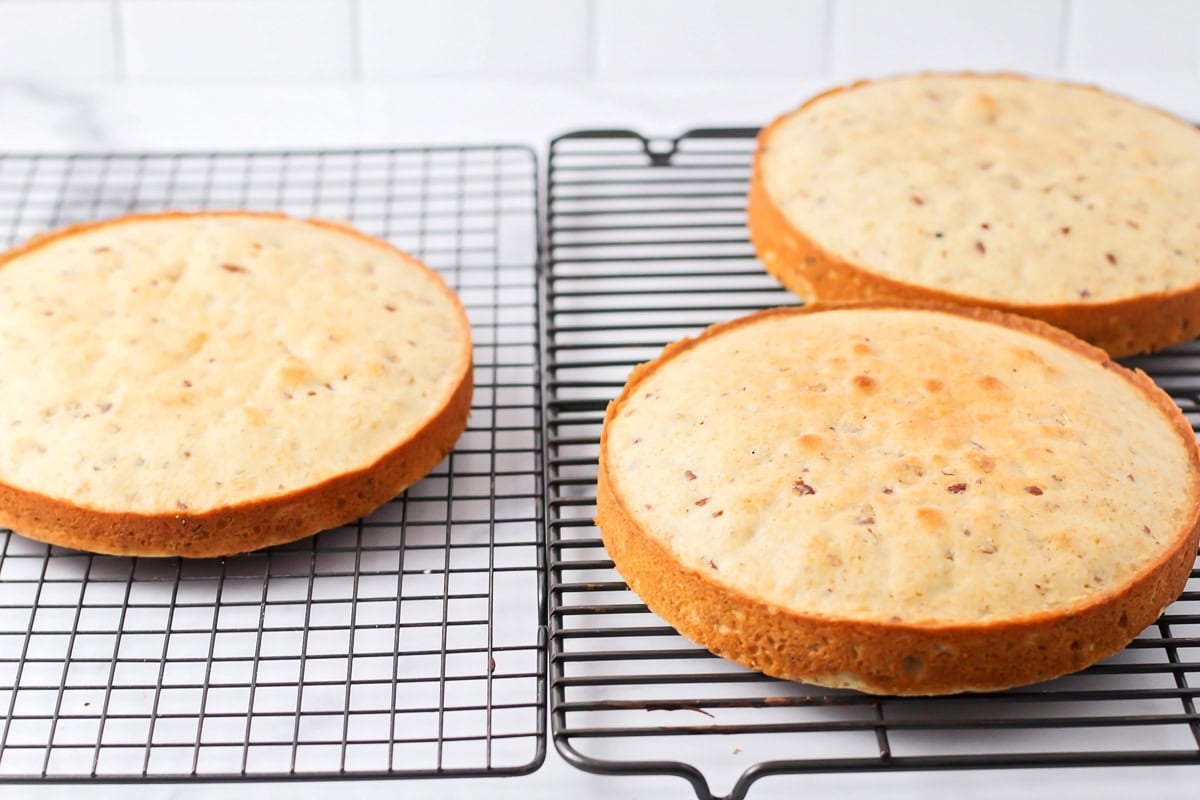 Three cake rounds cooling on a wire rack.