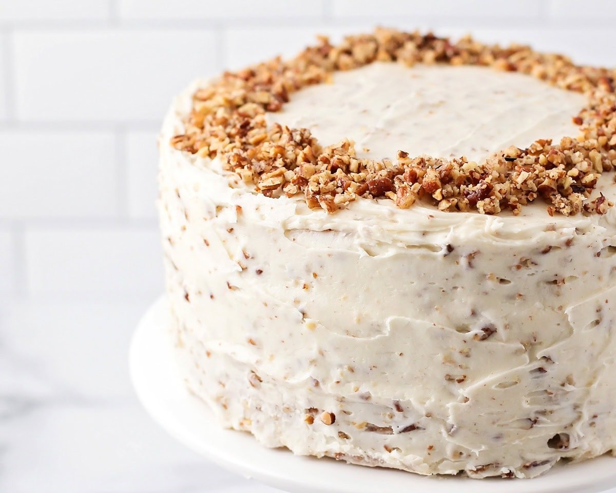 A frosted cake with chopped pecans on top.