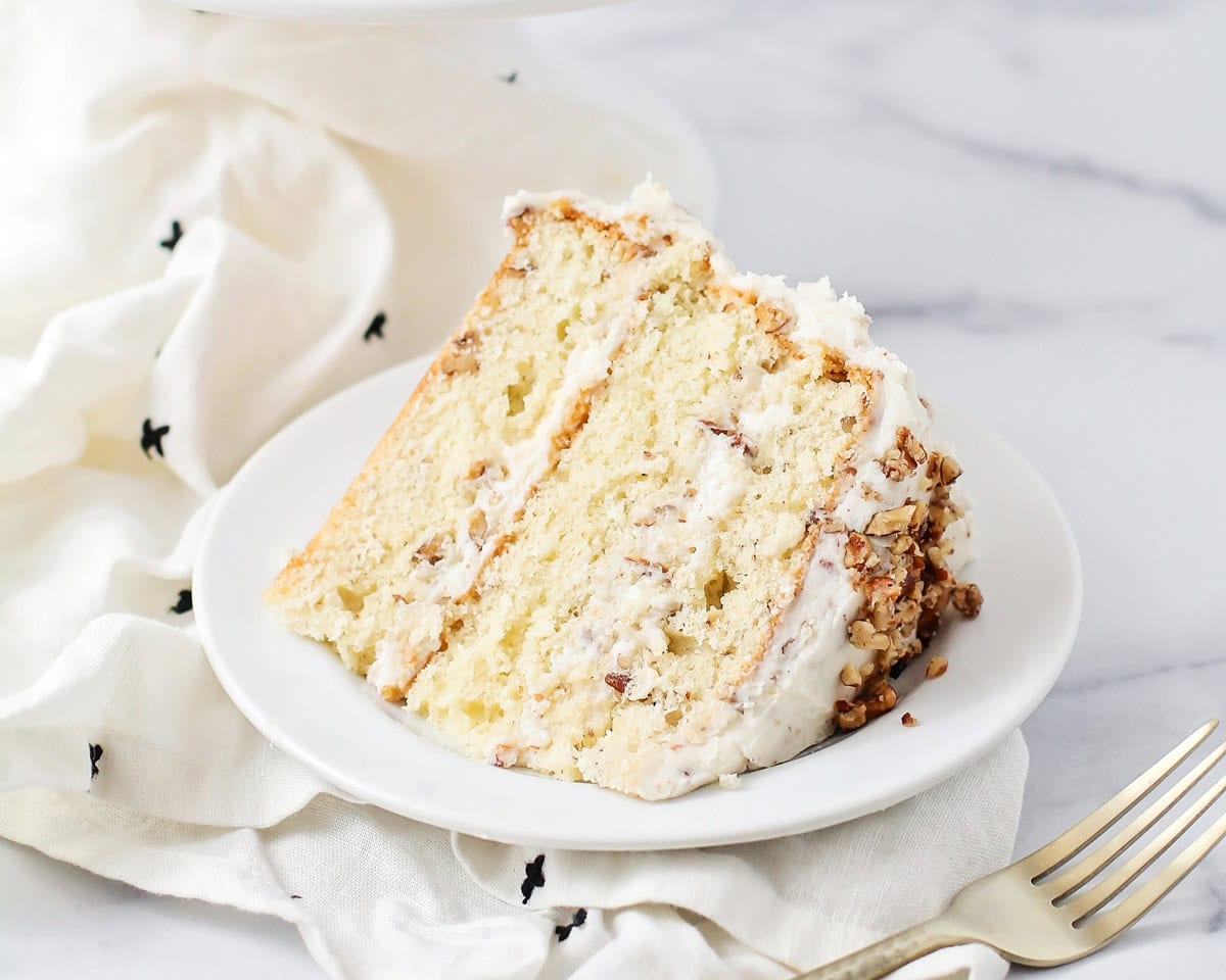 A slice of butter pecan cake on a white plate.