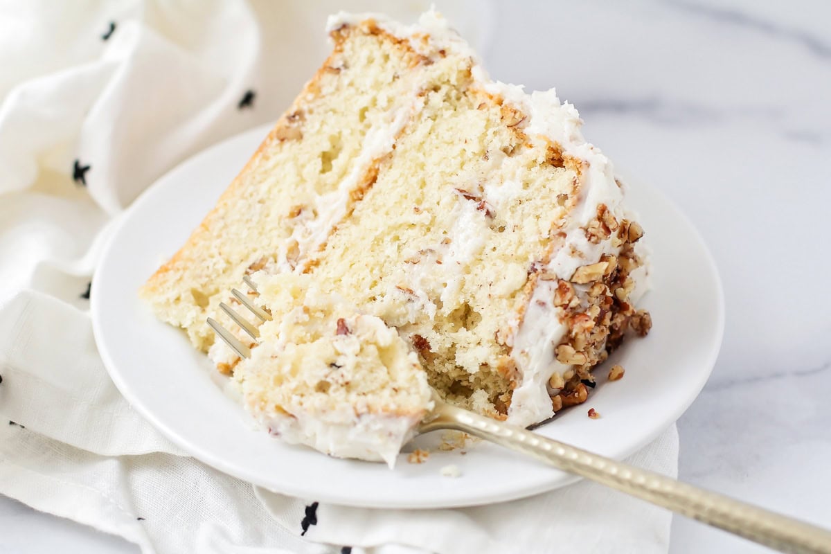 A slice of butter pecan cake on a white plate.