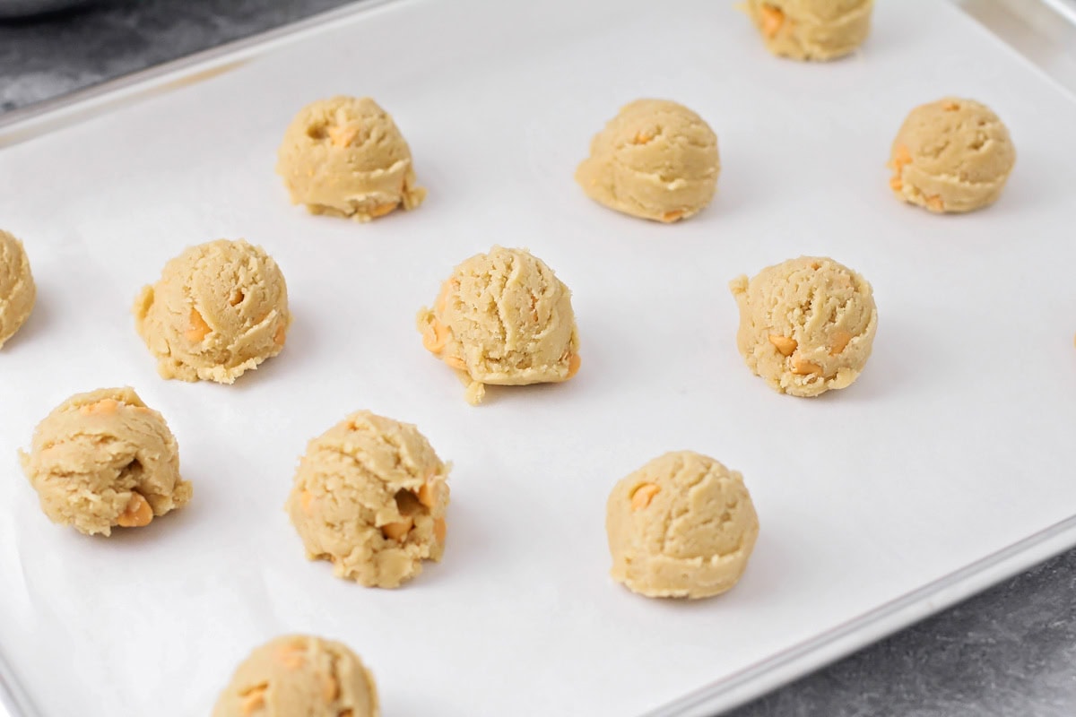 Cookie dough with butterscotch chips on cookie sheet.