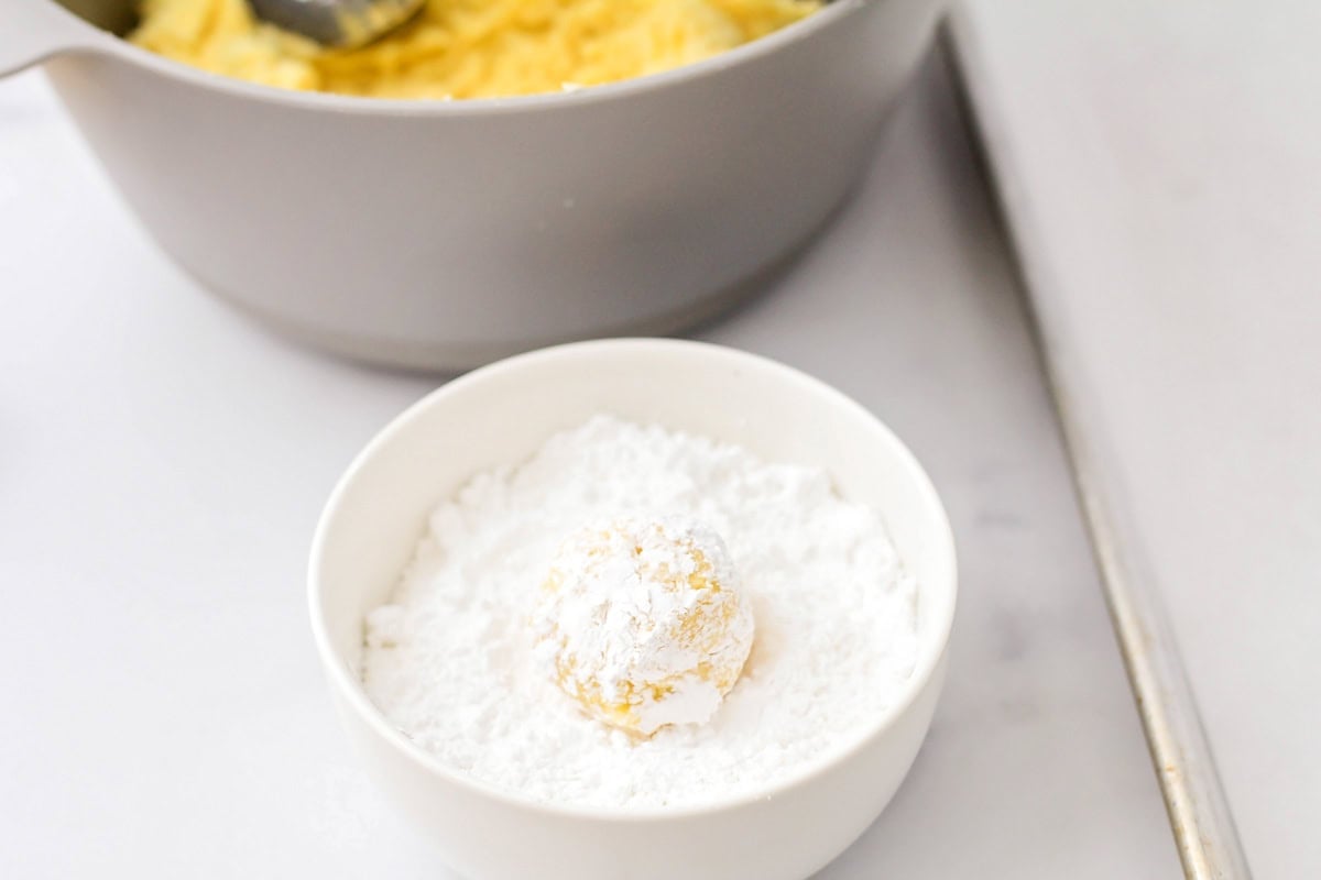 Dipping dough balls in powder sugar.