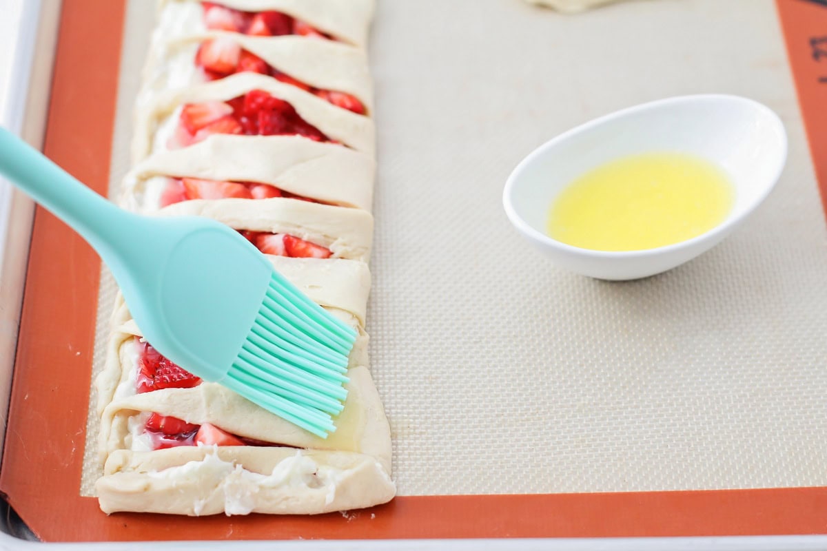 Brushing the melted butter on the crescent rolls.