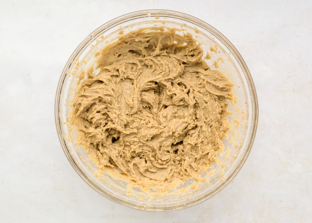 Cookie dough being mixed in glass mixing bowl.