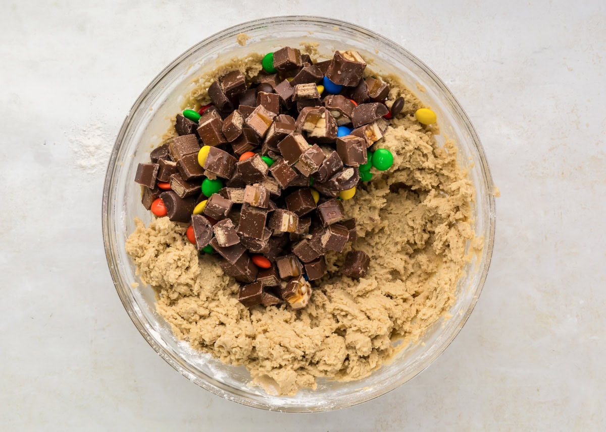 Chopped candy poured into bowl with cookie dough.