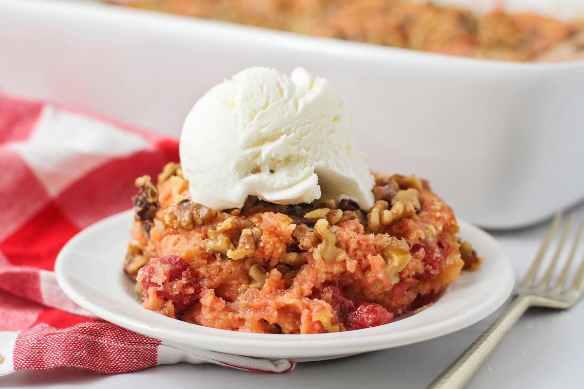 Close up image of cherry dump cake on white with vanilla icream.