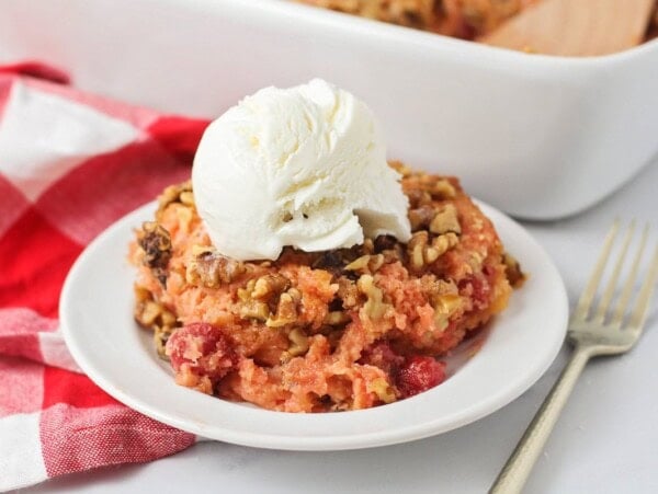 Cherry dump cake on plate with vanilla ice cream on top.