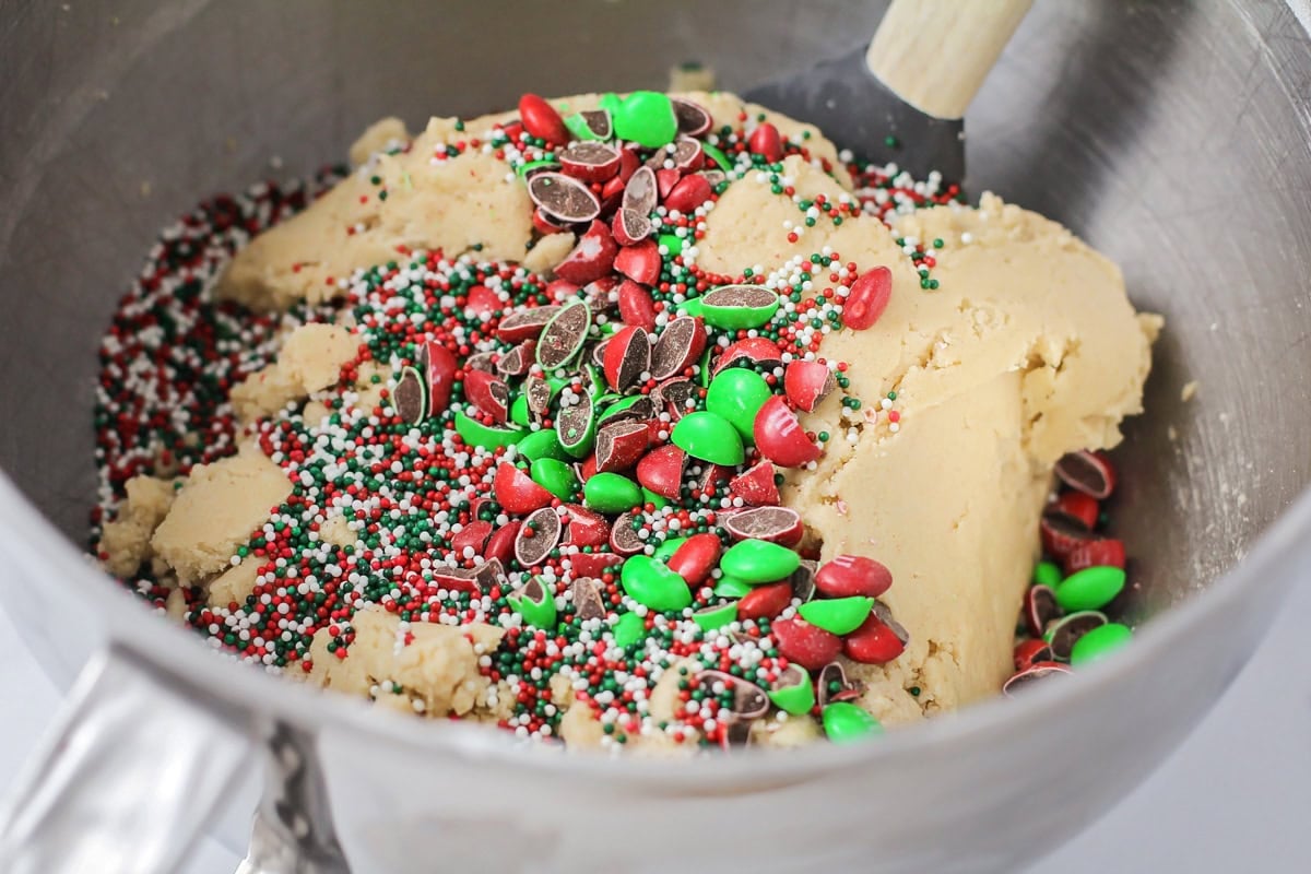 Adding M&Ms and sprinkles to cookie batter.