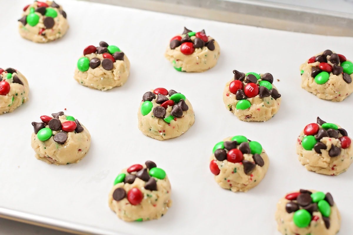 Topping cookie dough balls with M&Ms and chocolate chips.