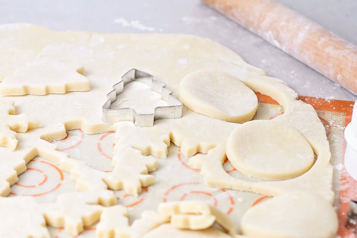 Cutting Christmas tree shaped cookies out of dough.