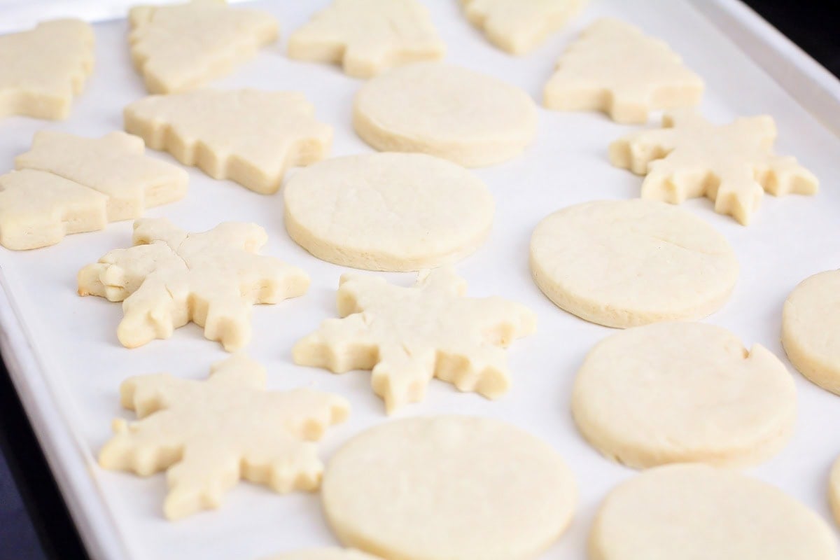 Snowflake, tree, and circle cookies on a lined baking sheet.