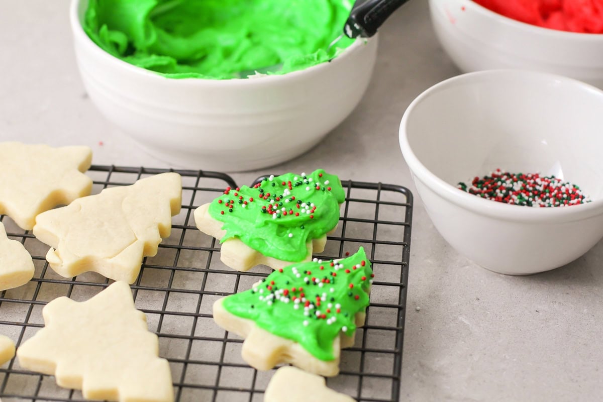 Green frosted Christmas tree cookies on a wire rack.