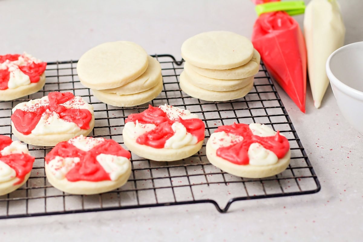 Cookies decorated like peppermints on a wire rack.