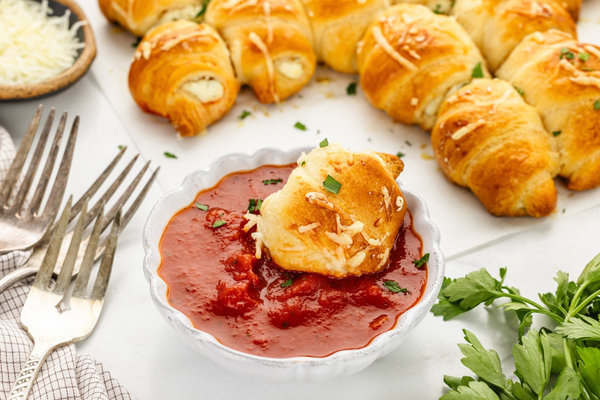 Dipping a piece of the crescent roll Christmas tree into marinara.