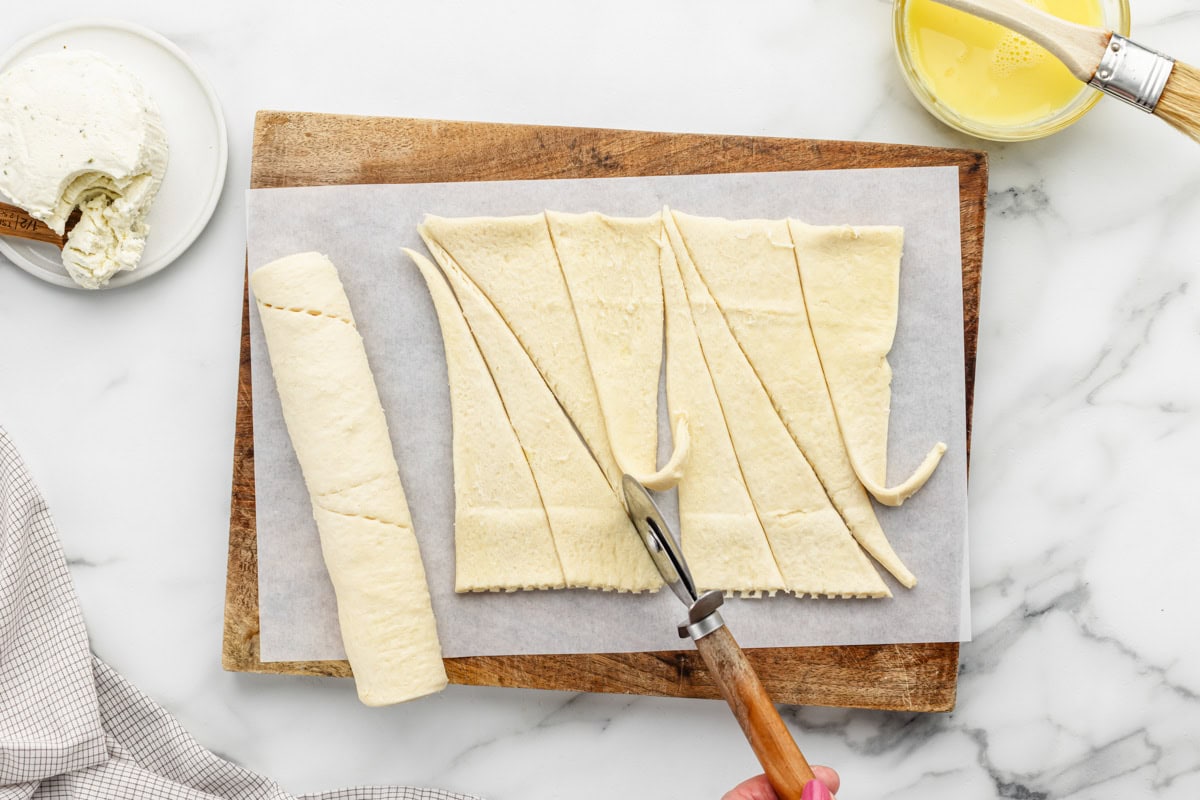 Cutting crescent rolls into triangles.