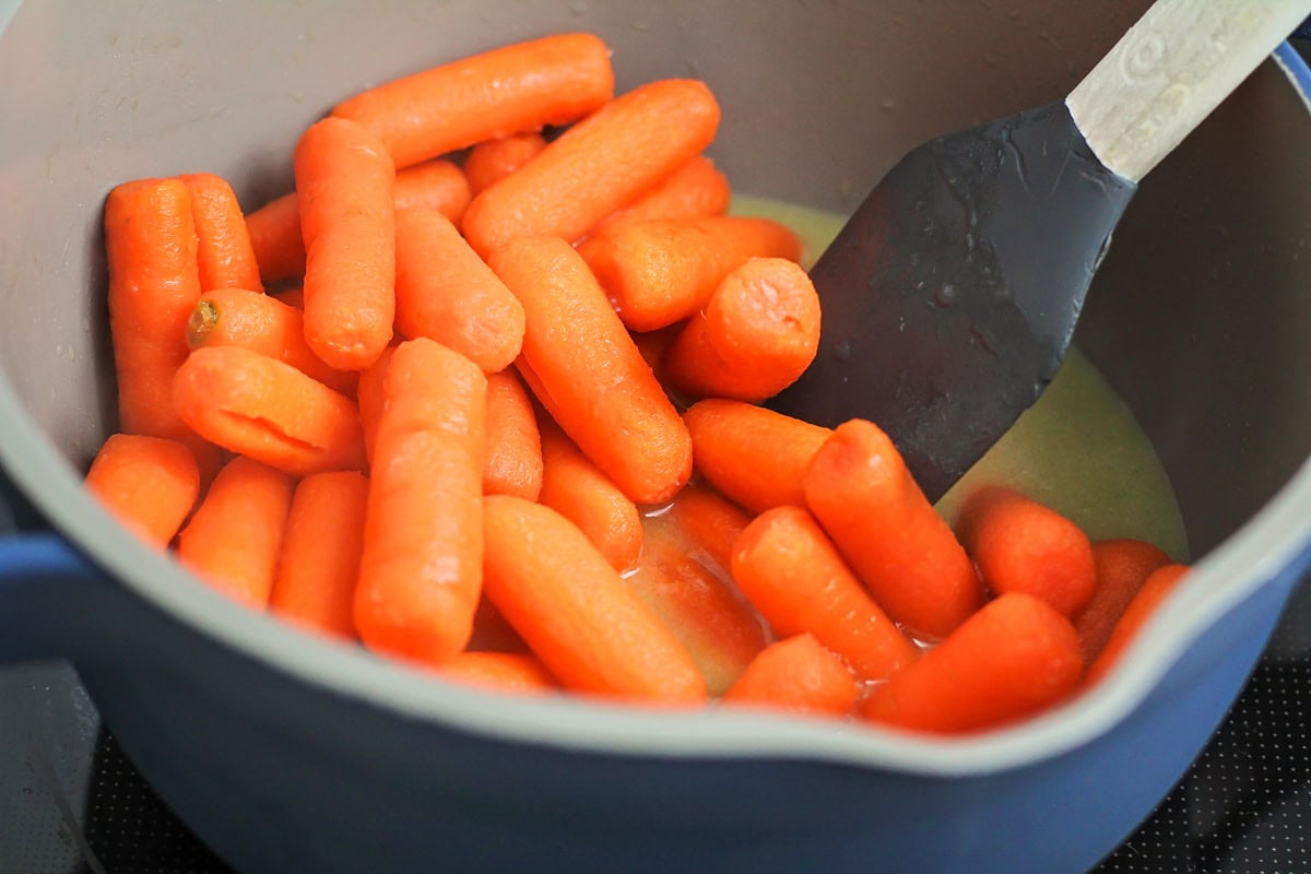 Glazed carrots being cooked in pot.