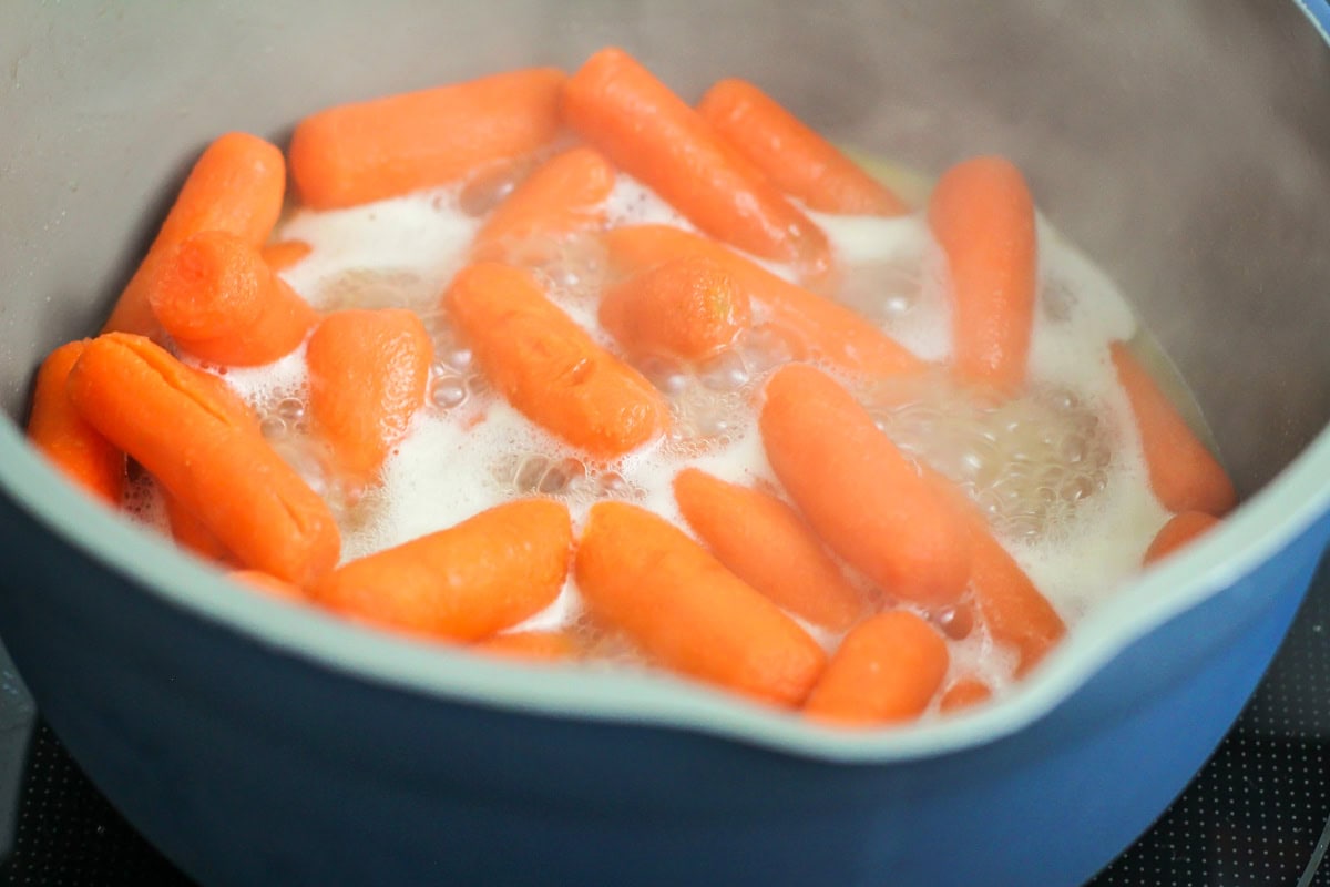 Baby carrots being cooked into glazed carrots.