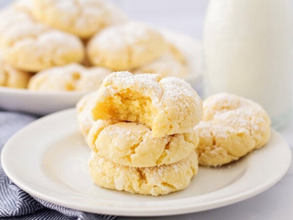 Gooey butter cookies stacked on each other on white plate.