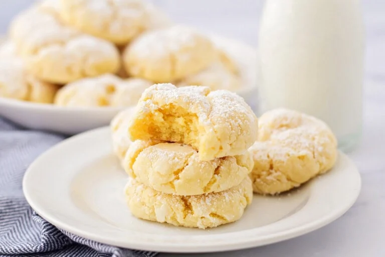 Gooey butter cookies stacked on each other on white plate.