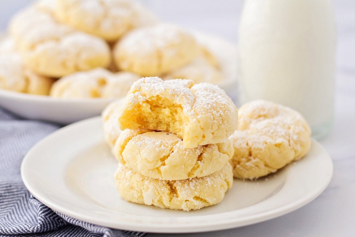 Gooey butter cookies stacked on top of each other on white plate.